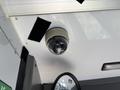 A dome security camera mounted on the ceiling of a vehicle