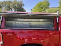 A red 2018 GMC Canyon with an open truck bed showcasing a silver aluminum cap and storage space inside