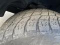 Close-up of a worn tire showing deep tread patterns with noticeable wear and embedded debris