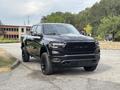 A 2021 RAM 1500 pickup truck in black with a bold front grille and alloy wheels parked on a road