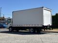 A white 2022 Isuzu NQR box truck viewed from the side with a large cargo area and a flatbed chassis