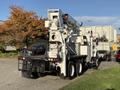 A 2011 International 7500 truck with a large aerial lift mounted on the back positioned for utility work