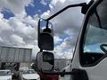 A 2022 International MV607 truck featuring a side mirror with a sturdy arm reflecting the sky and nearby vehicles