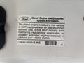 2009 Ford F-450 Super Duty with a label detailing diesel engine idle shutdown system information and compliance notes
