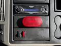 A dashboard of a 2010 International 4300 featuring a Panasonic stereo and a red warning light with an on/off switch below it