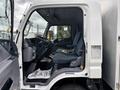 Interior view of a 2015 Mitsubishi Fuso FE160 showing two blue seats with seatbelts and a dashboard with controls and displays