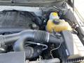 The image shows the engine compartment of a 2014 Ford F-150 with visible components including the engine block intake manifold and coolant reservoir
