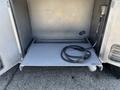 A silver storage compartment from a 2008 Workhorse W62 with a flat metal shelf and a coiled black cable resting on it