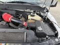 Engine compartment of a 2015 Ford F-350 featuring a red air intake hose a black air filter housing and a coolant reservoir