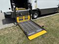 A wheelchair ramp extended from the rear of a 2020 Chevrolet Express with yellow safety markings and a metal mesh surface
