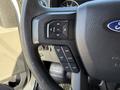 Close-up of a steering wheel control panel in a 2018 Ford F-150 featuring buttons for navigation and cruise control settings