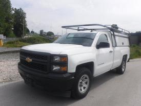 White 2015 Chevrolet Silverado 1500 with a black grille and a roof rack parked on a road