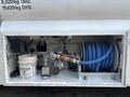 A section of a 2010 Freightliner M2 106 with a blue hose coiled on a reel a spray nozzle connected to a metal fitting and a bucket labeled with the word "MATEX"