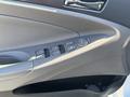A close-up view of the driver's side door panel of a 2015 Hyundai Sonata showing window controls and a speaker grille