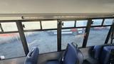 A 2021 Ford Transit van parked outside visible through a bus window