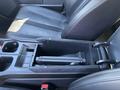 The interior console of a 2023 Fisker Ocean showing storage compartments and armrest in black leather upholstery