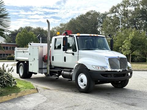 A 2008 International 4300 truck with a white cab and a flatbed equipped with a storage compartment and a red tool box on the side