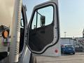A 2016 Freightliner M2 106 truck door is open showing the black interior panel and window with a view of the side mirror