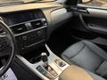 Interior of a 2013 BMW X3 featuring a black leather seat center console and dashboard with controls and a gear shifter visible
