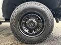 A black alloy wheel with a rugged tire designed for off-road use featuring a prominent tread pattern and a bold design