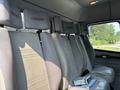Interior seats of a 1999 Freightliner FL80 with gray upholstery and headrests arranged in a row, showing a binder on the seat and no visible driver position