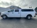 A white 2012 RAM 2500 pickup truck with an extended cab and a camper shell on the bed is shown from the side