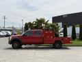 A red 2013 Ford F-550 with a flatbed and equipment box is parked with palm trees visible in the truck bed