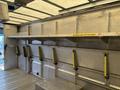 A 2012 Ford E-450 Super Duty with an empty cargo area featuring metal shelves and yellow safety handles attached to the walls