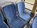 Blue patterned bus seats inside a Grande West Vicinity with a yellow handrail visible in the foreground