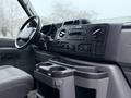 Interior of a 2013 Ford E-350 with a dashboard featuring controls for audio and climate settings and cup holders in the center console