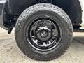 A black alloy wheel with a large tire featuring an off-road tread design mounted on a 2013 Ford F-250 SD