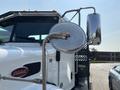 A shiny side mirror of a 2020 Peterbilt 330 truck with a prominent logo on the side and a reflective surface showing the truck's body