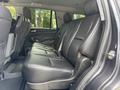 Interior view of a 2017 Chevrolet Tahoe showing the second row of black leather seats with seat belts and armrests