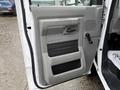 The interior door panel of a 2013 Ford Econoline features a gray plastic design with a handle a window crank and storage compartments