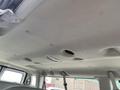 The interior ceiling of a 2010 Ford Econoline showing a fabric surface with several light fixtures and a hole in the material