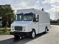 A 2017 Freightliner MT45 delivery truck with a white exterior and large front windows parked on a driveway