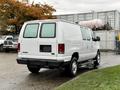 A white 2006 Ford Econoline van with a rear view showing two side windows and no visible license plate