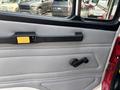 Interior door panel of a 1999 Freightliner FL80 featuring a black handle and a manual window crank with a textured gray fabric trim
