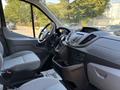 Interior view of a 2016 Ford Transit 150 showing the driver's seat dashboard and steering wheel with controls and storage compartments