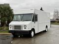 A white 2018 Ford E-450 delivery van with a boxy shape and large front windshield parked on a paved surface