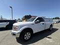 A 2019 Ford F-150 in white with a truck cap on the bed and alloy wheels parked in a lot