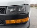 A close-up of the front of a 2021 Chevrolet Express showcasing the headlights and turn signal with raindrops on the surface