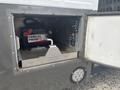A silver 2020 Chevrolet Express with an open door revealing a mounted battery labeled CANADA PROOF and various cables and connections inside the compartment