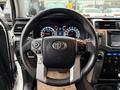 Steering wheel of a 2018 Toyota 4Runner featuring control buttons and the Toyota emblem with a dashboard display showing gauges and settings