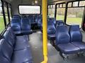 Interior of a 2019 Chevrolet Express featuring blue fabric seats arranged in rows with a yellow pole in the center