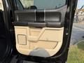 The interior door panel of a 2021 Ford F-350 SD featuring a two-tone design with black and beige materials and a textured handle