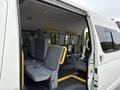 A 2009 Toyota Hiace with an open side door showing rows of grey seats and yellow handles inside the van