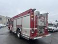 A red 2006 E-One Fire Truck with dual rear wheels featuring multiple compartments and equipment, visible hoses and a large silver ladder mounted at the back