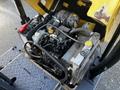 A 2013 Yanmar C12R-B engine with various components including wires a radiator and hoses visible in the compartment