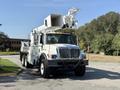 A 2006 International 7500 truck equipped with a large aerial lift and work bucket mounted on the top, featuring a white and light blue color scheme and a black chain around the front bumper